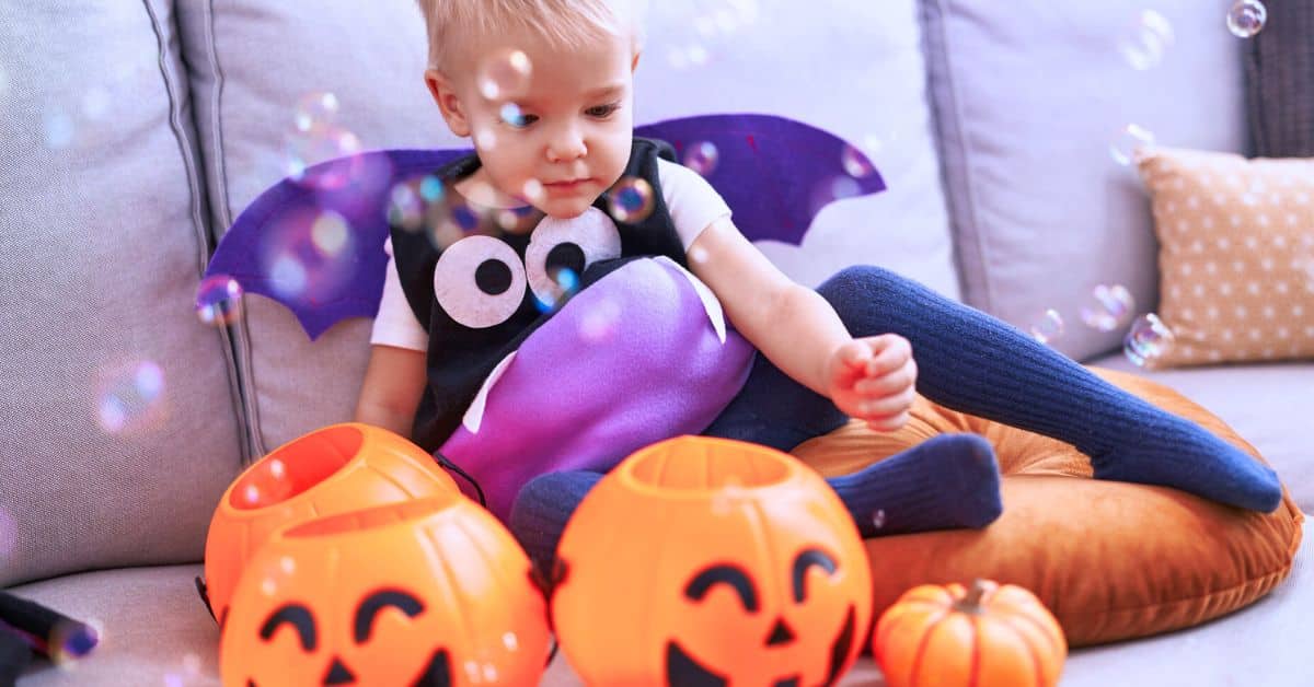 toddler in Halloween costume with pumpkins for Fun Toddler-Friendly Halloween Party Ideas